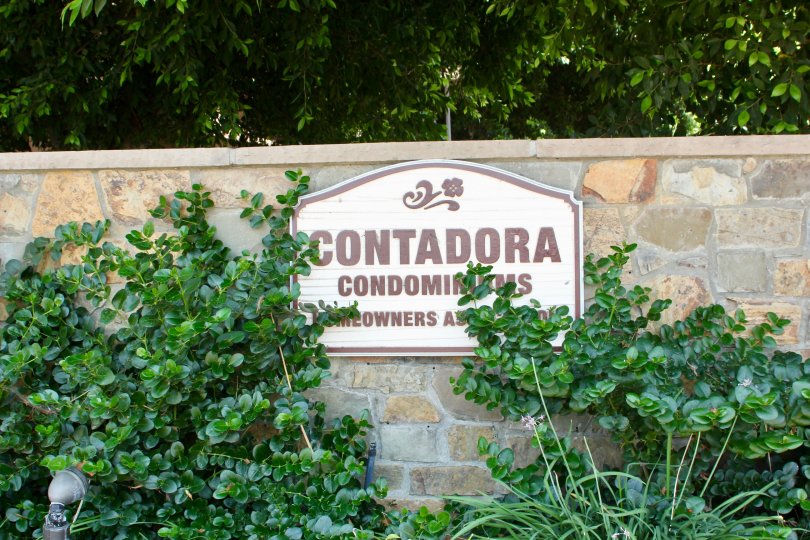 Bushes sit in front of a wall and partially cover a sign at the Contadora community.