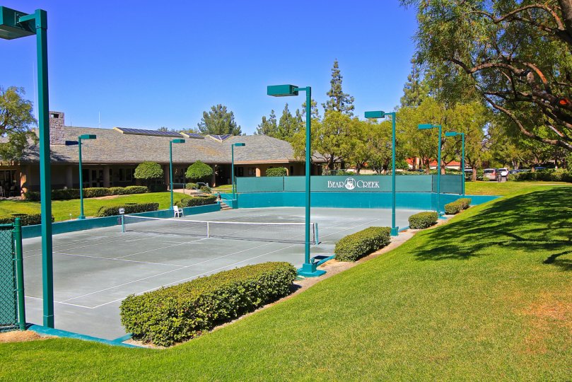 A teal green fence surrounds a tennis court at the Fairway Estates at Bear Creek.