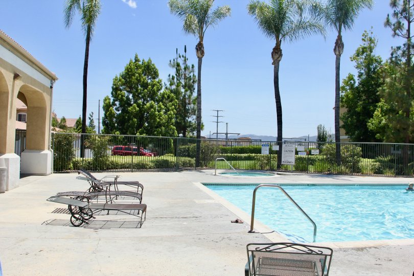 Madison Park Villas murrieta California pool surrounded by grid valley, tall trees and resting chairs at side
