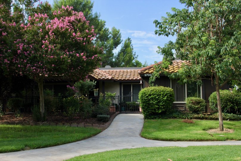 A sunny day in the Victoria Village community in Riverside, California. Lovely tile roof home with a crape myrtle tree and wrought iron porch rails.