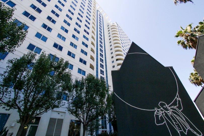 On a large black sculpture a man outlined in white holds a circle in front of Harbor Place Tower