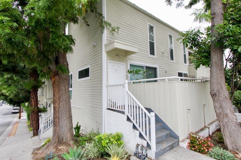 Side view of the house with flowers planted at the entrance and a lush green trees at 3101 Fifth in Santa Monica, California
