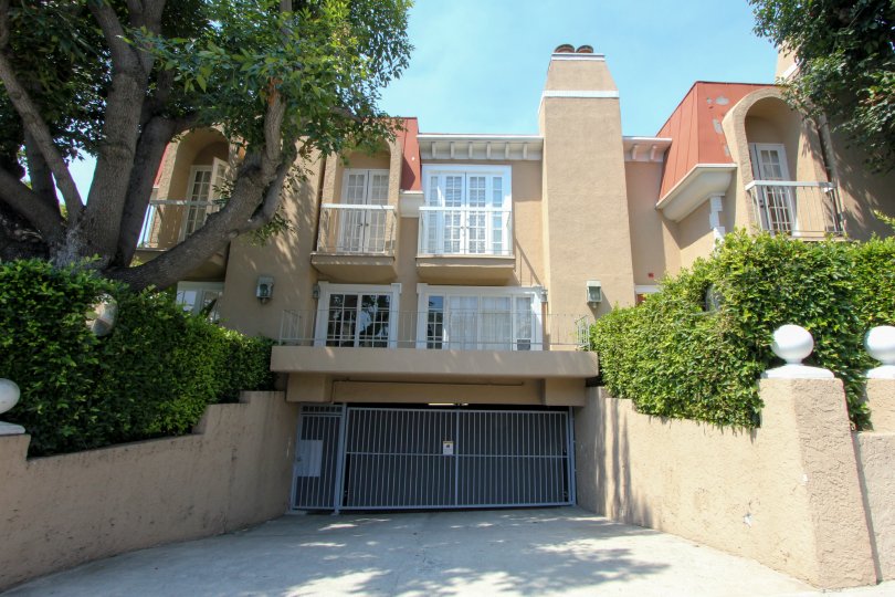 A BUILDING WITH A SMALL GATE INFRONT OF AND ALSO CLOSED SOME GREEN PLANTS ALSO NEAR TO THE HOUSE.