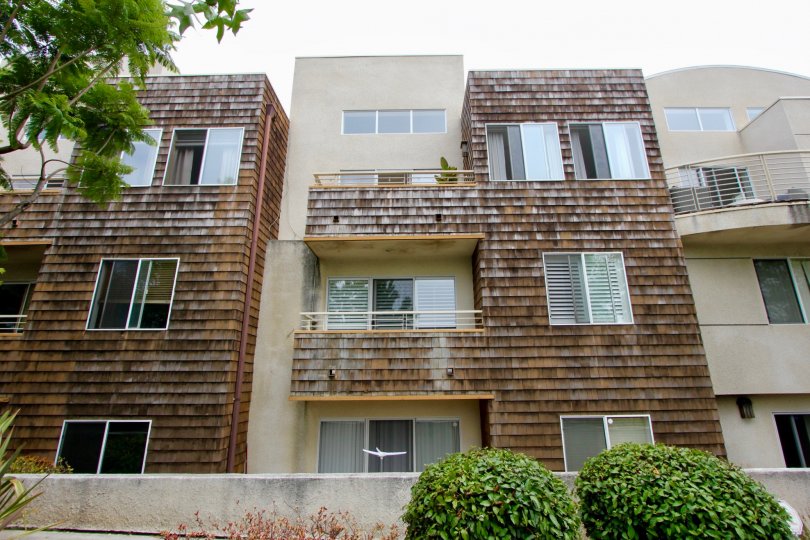 Weathered brown three story apartment building with balconies on second and third stories.