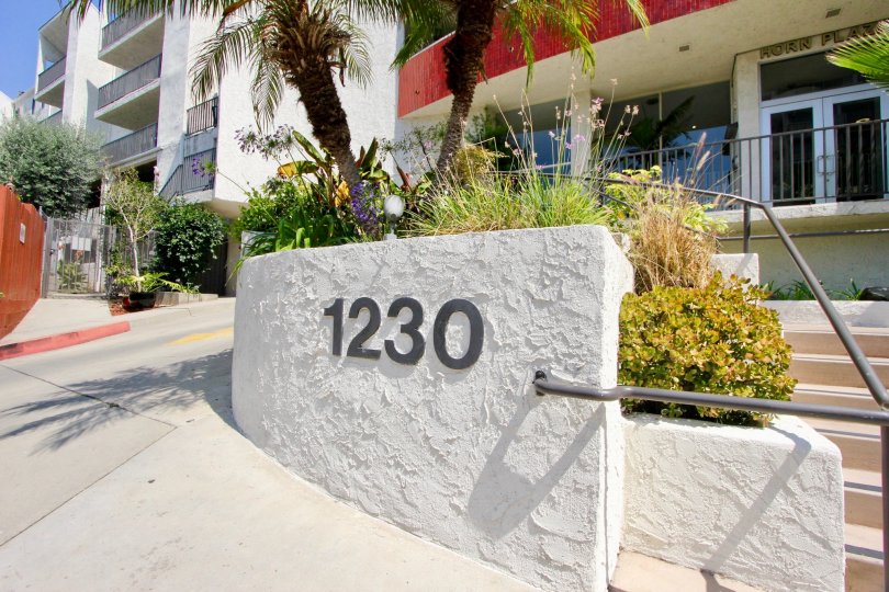 The street number of a facility displayed on a stone wall near steps in the Horn Plaza community of West Hollywood, California.
