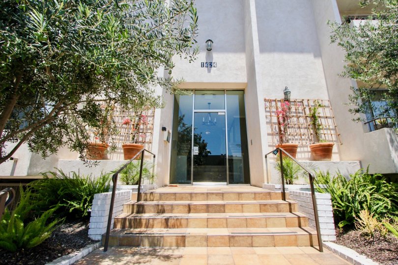 Exterior view of front entrance, stairwell, and trees at 1424 Amherst in West LA, California on a sunny day