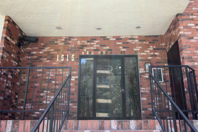 The glass front door of a brick building with the buildings address in Brighton Manor