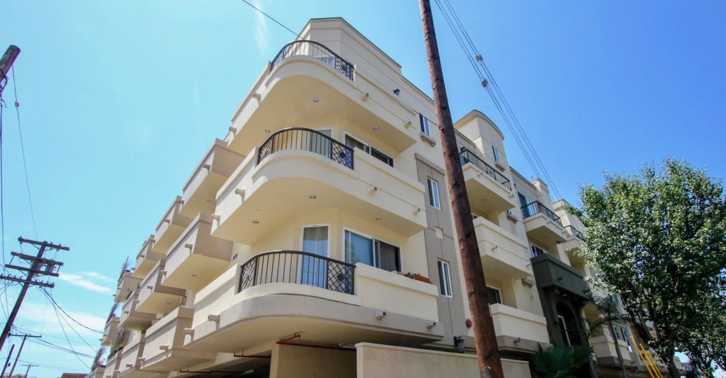 Three level condo has side wrap around balconies in ivory color next to power lines and telephone polls