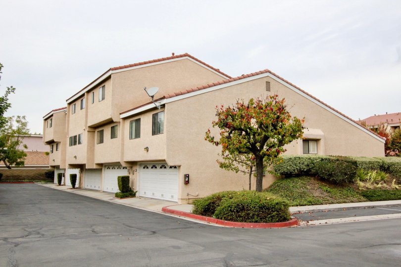 THIS IS THE SIDE VIEW OF THE VILLAS WITH SHED ALONG THE TREES, PLANTS, ROADWAY LOCATED IN BUENA PARK