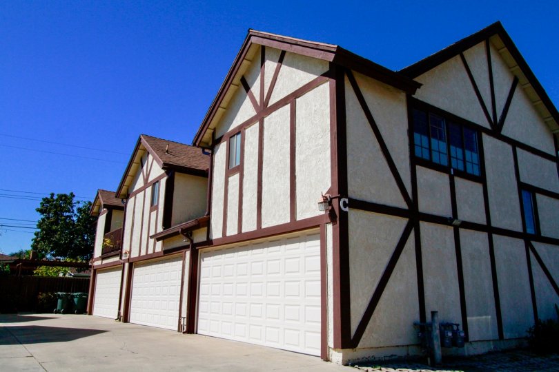 Row of white stucco two-story units with brown accenting and dual garages at Picadilly Terrace in Costa Mesa, CA