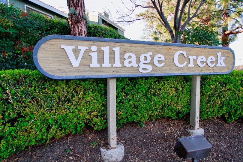 Village Creek sign with bushes and trees on a cloudy day.