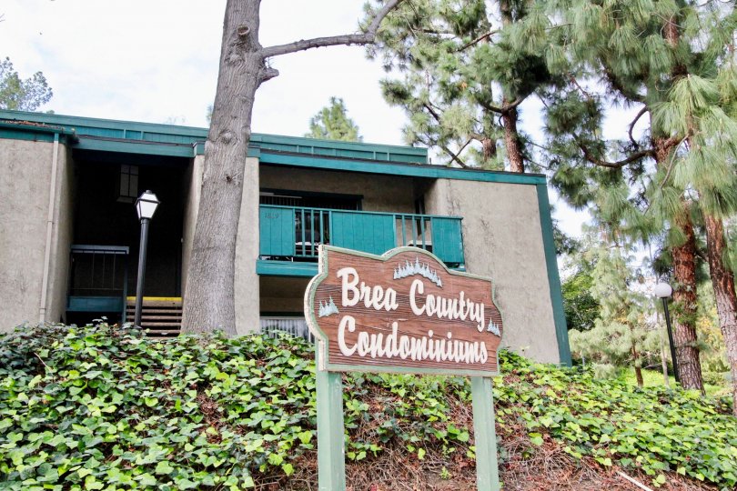 A sign in the Brea Country community with trees and other plants on a cloudy day.