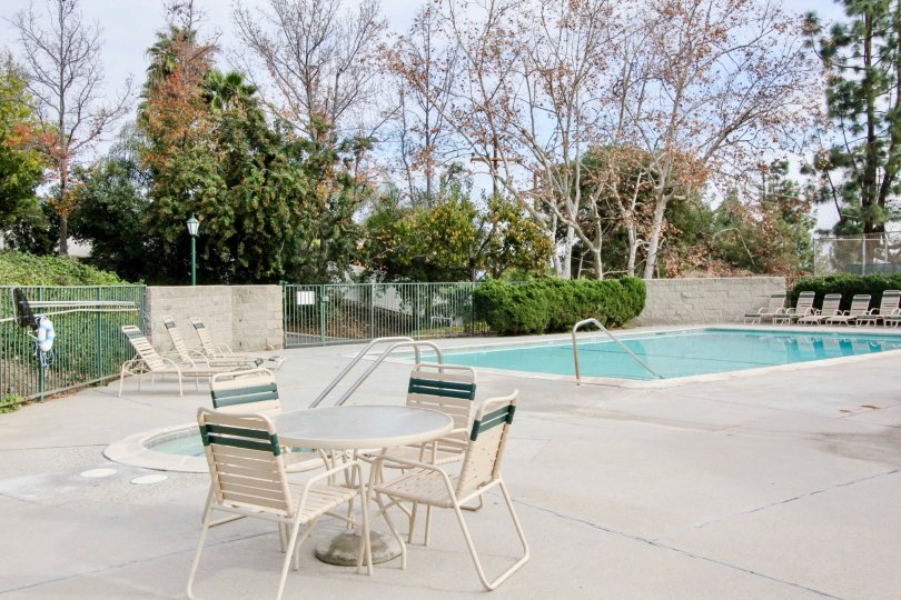 A pool in Casa Del Vista with deck chairs and tables enclosed with a fence.