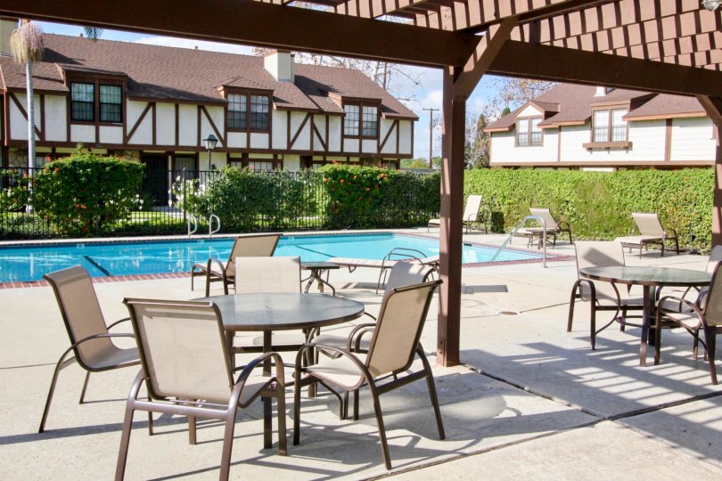 A deck by the pool of Chelsea Park Estates with deck chairs and tables.