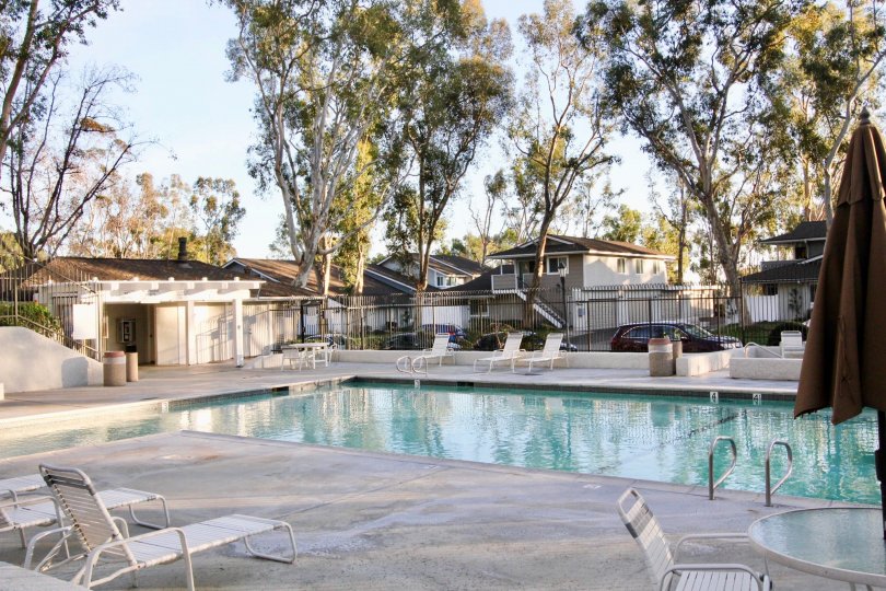 A fenced in pool in Coyote Hills Bluffs with deck chairs and tables.