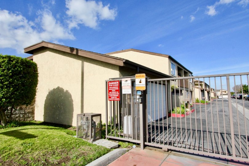 A gate and building on a sunny day in Garden Terrace Townhomes in Garden Grove California