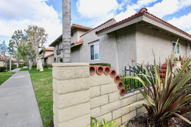 A neighborhood with several homes; a fence with pipe-like features, with trees in the front lawns.