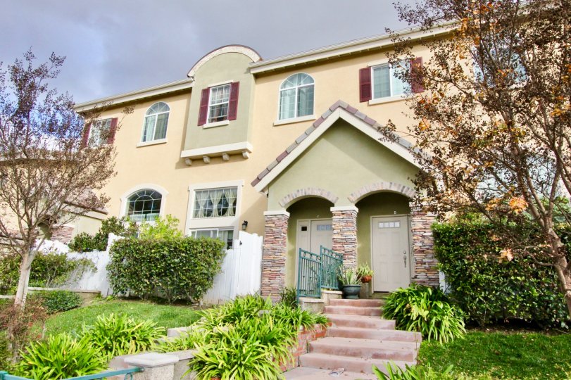 two story mansion front with staircase entrance and greenery around