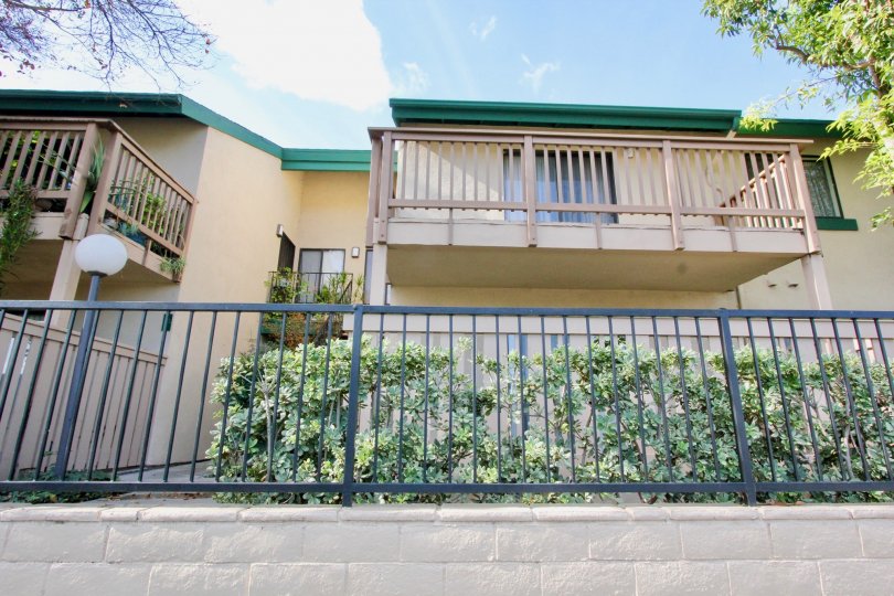 a housing view with a fence in front with a small lamp and balconies on second floor
