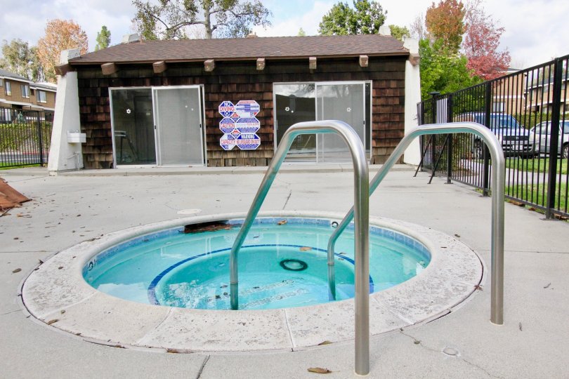 THIS SHOWS THE VERY SMALL SWIMMING POOL THAT IS SURROUNDED BY THE GATE WALLS AND NEARBY SHOWING TREES, CARS IS IN THE CITY OF GARDEN GROVE
