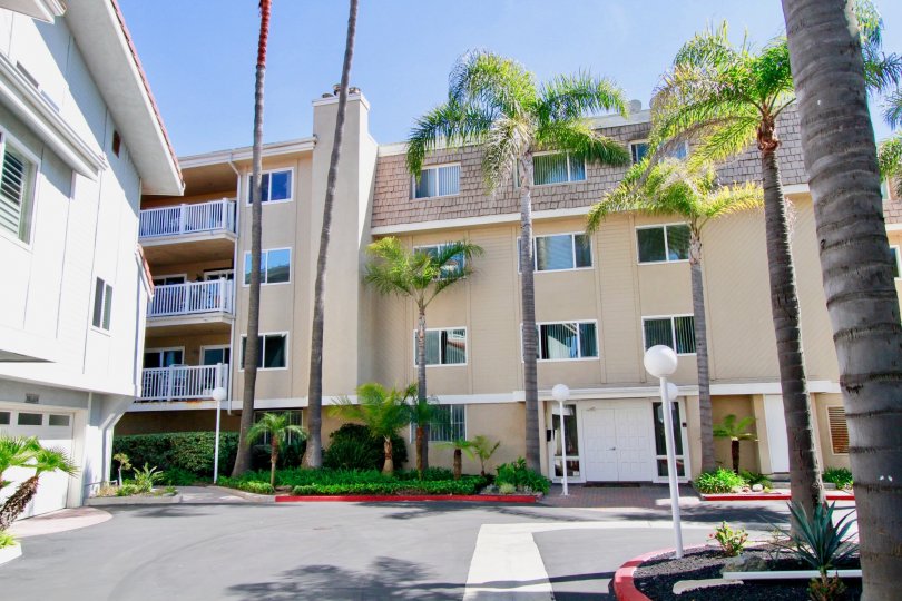 A four story condominium structure with many windows sits behind a driveway at Bayport in Huntington Beach CA