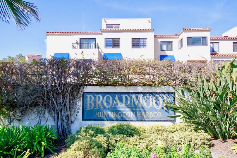 Broadmoor Huntington Harbor, Huntington Beach, California. Large sign, white stucco building, red tile roof, blue awnings.