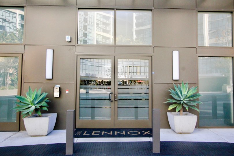 doors into Lennox complex flanked by two potted plants with a blue weclome mat