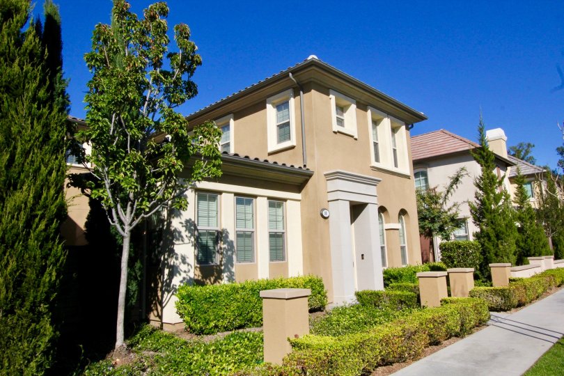 A two story brown home with a gray archway entrance inside Stonetree Manor in Irvine CA