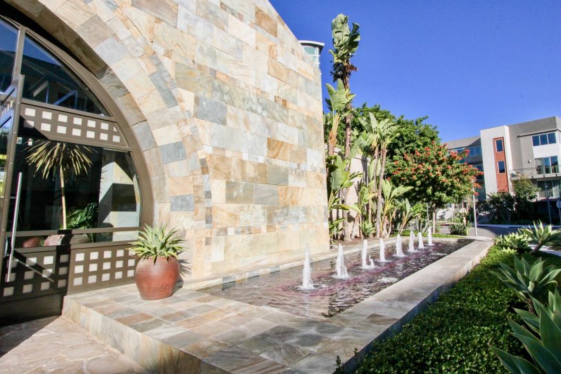 An appartment entrance with greenery and fountains surrounding
