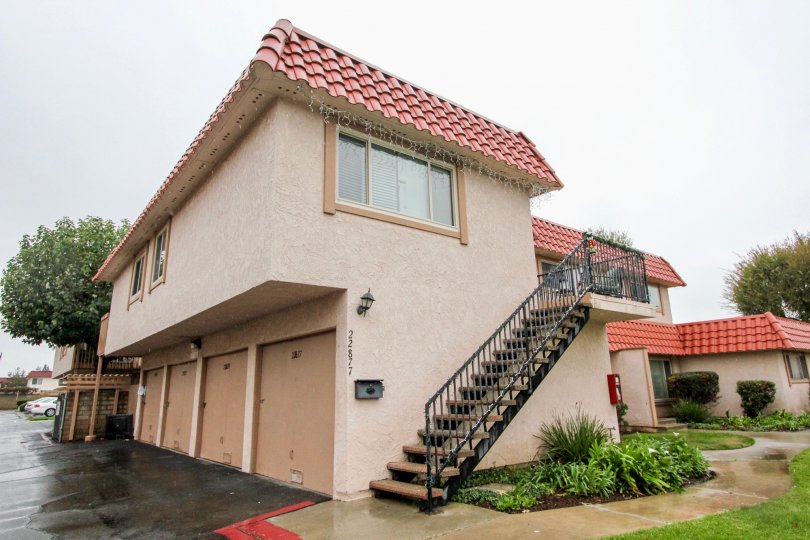 A taupe codo building with a red tile roof on a rainy day in the Rancho Viejo Condos I community in Lake Forest, CA