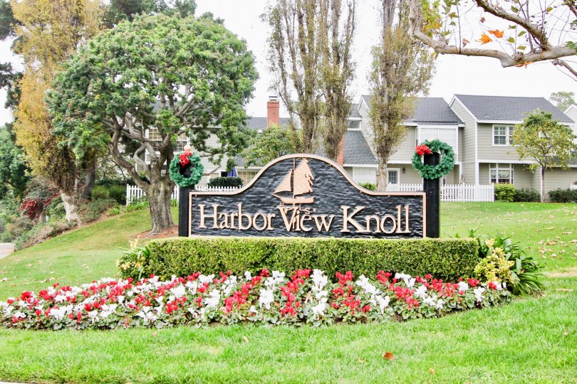 THE HOUSE IN THE HARBOR VIEW KNOLL WITH THE NAME BOARD, LAWN, FLOWER PLANTS, TREES