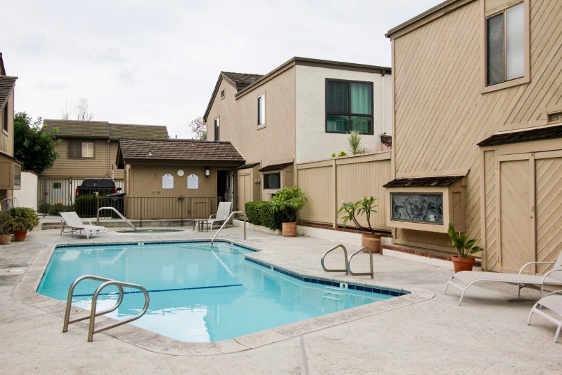 A cloudy day in the Newport Glen with a swimming pool and white color chairs.