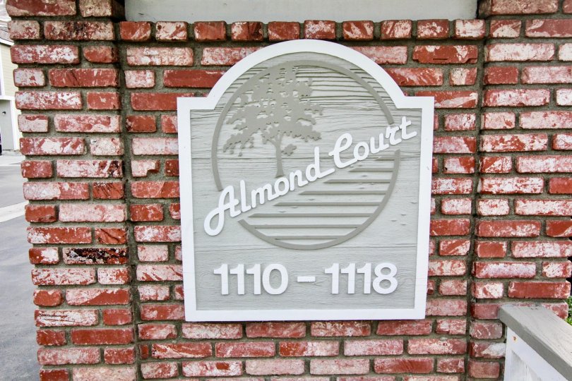 The gray sign for the Almond Court community with red brick