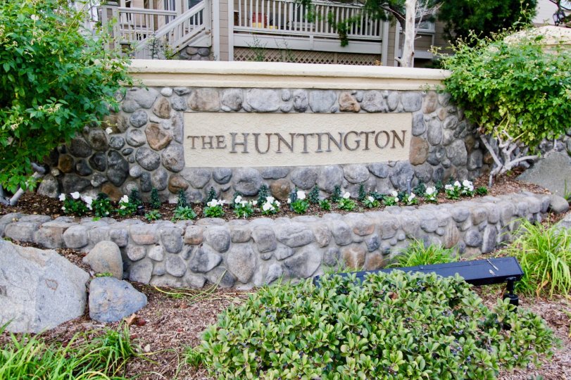 The sign for the Huntington Community with flowers and bushes