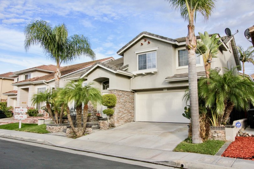 A gray home with palm trees in Sycamore Crossing on a sunny day