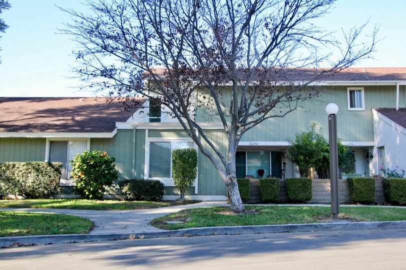 A light colored home with bushes in Village San Juan Townhomes community in San Juan Capistrano, California.