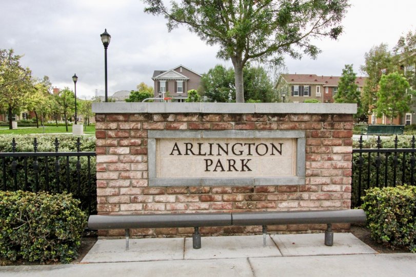 An overcast day by an Arlington Park sign in Meriwether with buildings, light poles, and trees all behind the sign