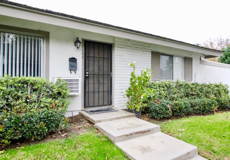 A simple bungalow with gated front doors and white walls in the Sycamore Gardens community.