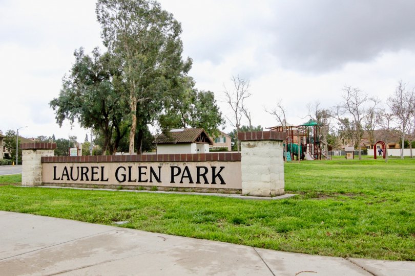 An overcast day by a Laurel Glen Park sign in Travilla with a playground behind it as well as trees scattered around