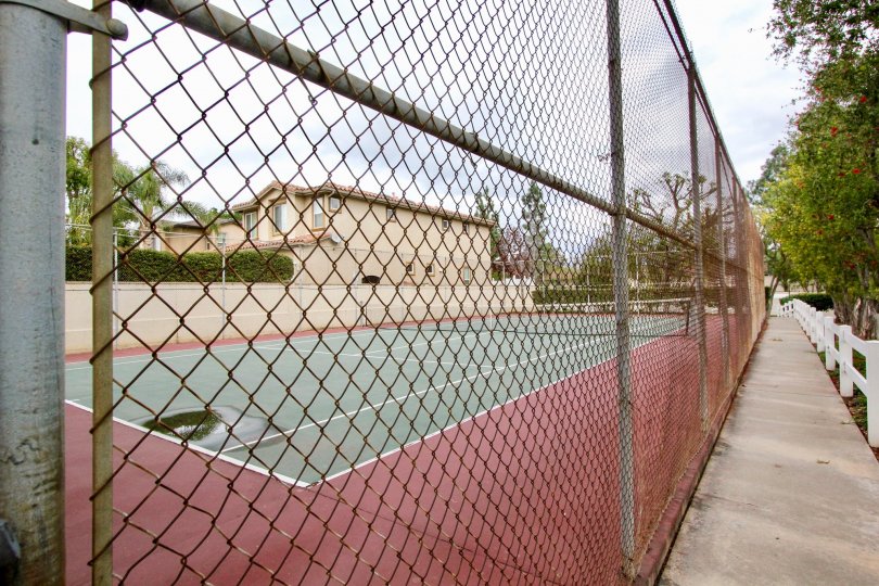 Tennis court surrounded by a metal fence in the community of Jamestowne Homes.