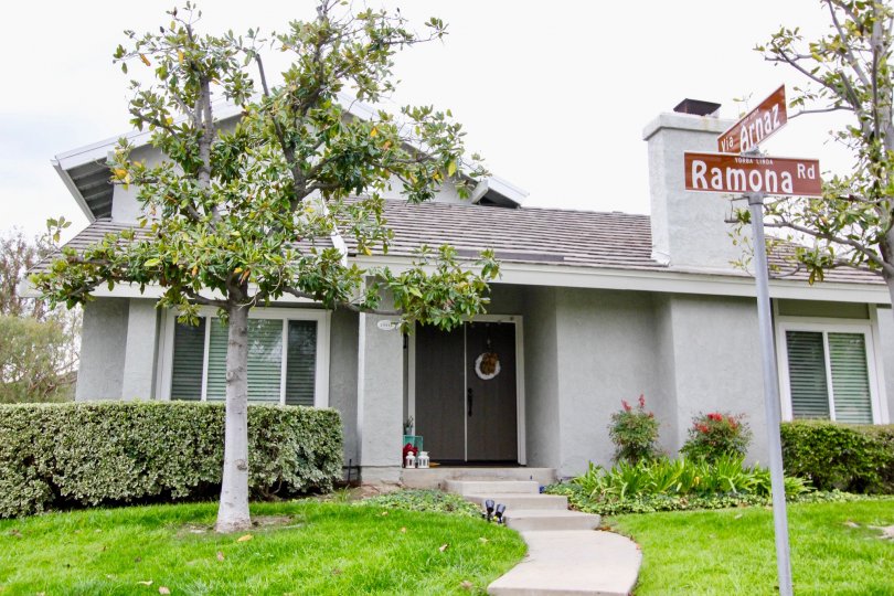 Front to the entrance of villa in Rancho Dominguez Townhomes has Street board with lawn and trees
