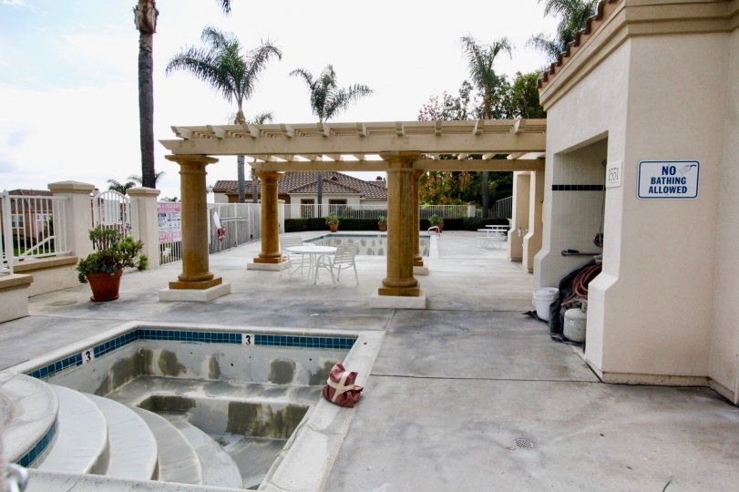 An empty and dirty hot tub across from a swimming pool in Aldea in CArlsbad CA