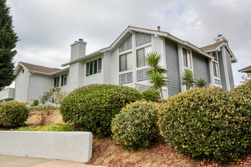 A home surrounded by shrubbery on a cloudy day at the Carlsbad Crest community.