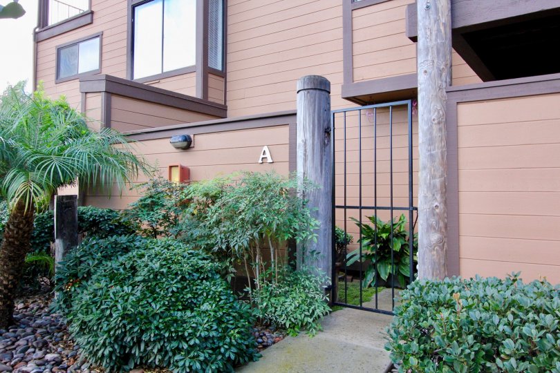 An outdoor fence and lush green foliage lead to Unit A in Windsong Palms.