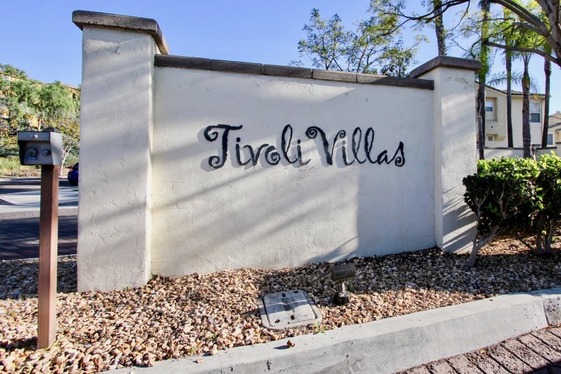 A simple white concrete signage of the Tivoli Villas community under a shade.