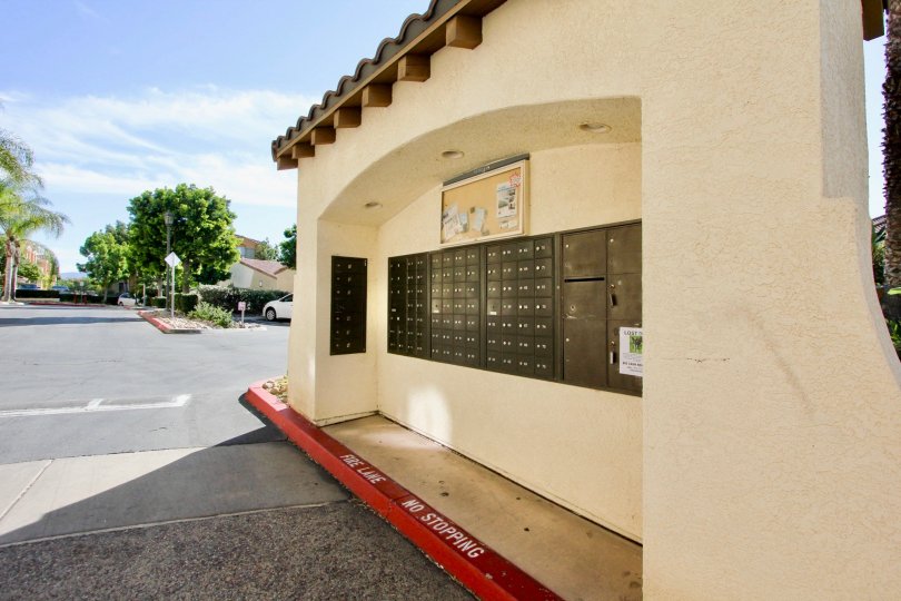 A tall wall of many mailboxes next to a road in the Villagio community of Chula Vista, California.