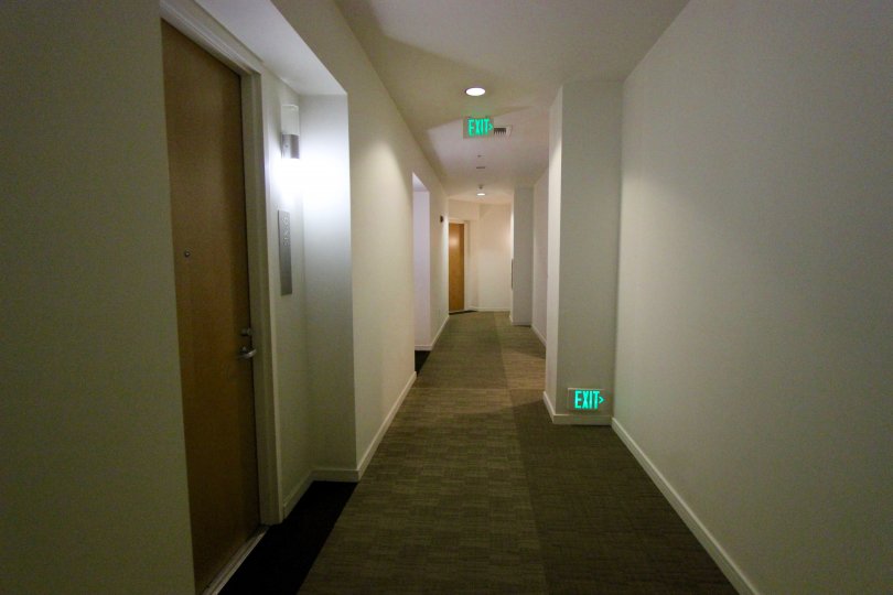A hallway with exit signs and several doorways with lighting accents at 350 West Ash