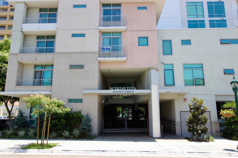 Tall pink and brown building with sign over lobby at Acqua Vista in Downtown San Diego CA