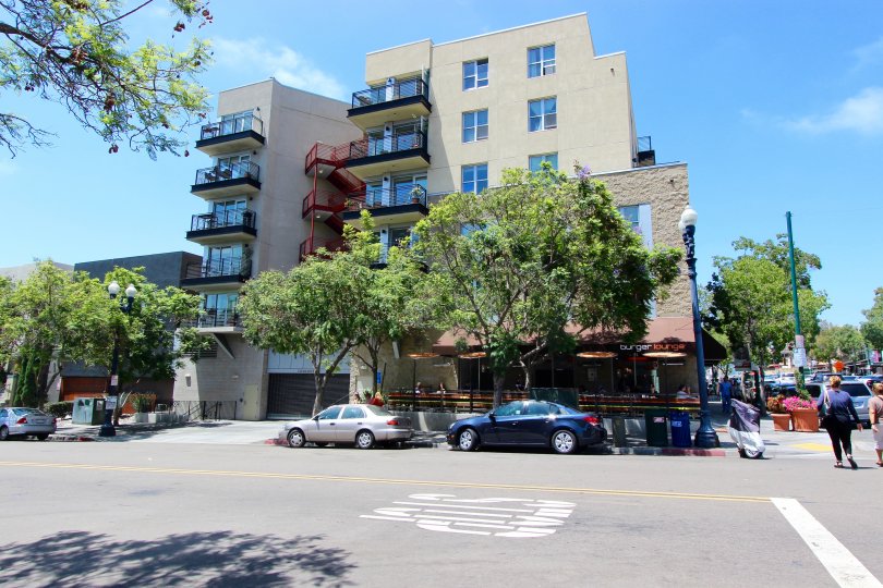 The exterior of the Bella Via building with exterior stairways, glass balconys, and the Burger Lounge in the ground floor.