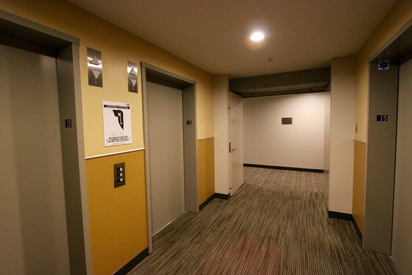 Elevators face each other in a tan and mustard hallway at Smart Corner.